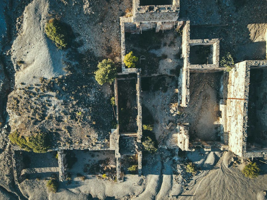 Explore the aerial perspective of ancient stone ruins surrounded by rugged landscape.